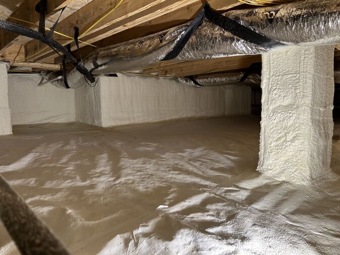 Crawl space with insulated walls and plastic vapor barrier on the ground, exposed ductwork, and wooden beams visible on the ceiling.