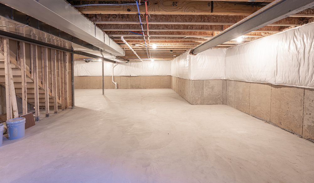 Unfinished basement with exposed wooden ceiling beams, concrete floor and walls, visible ductwork, and stairs leading up.