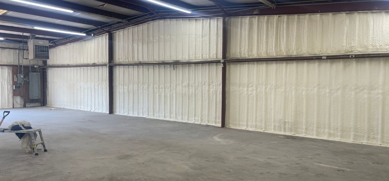 Interior view of a commercial metal building with closed-cell spray foam insulation applied to the walls for improved energy efficiency and moisture control.